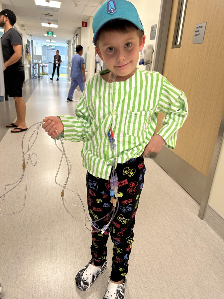 Young boy in a hospital corridor, holding tubes
